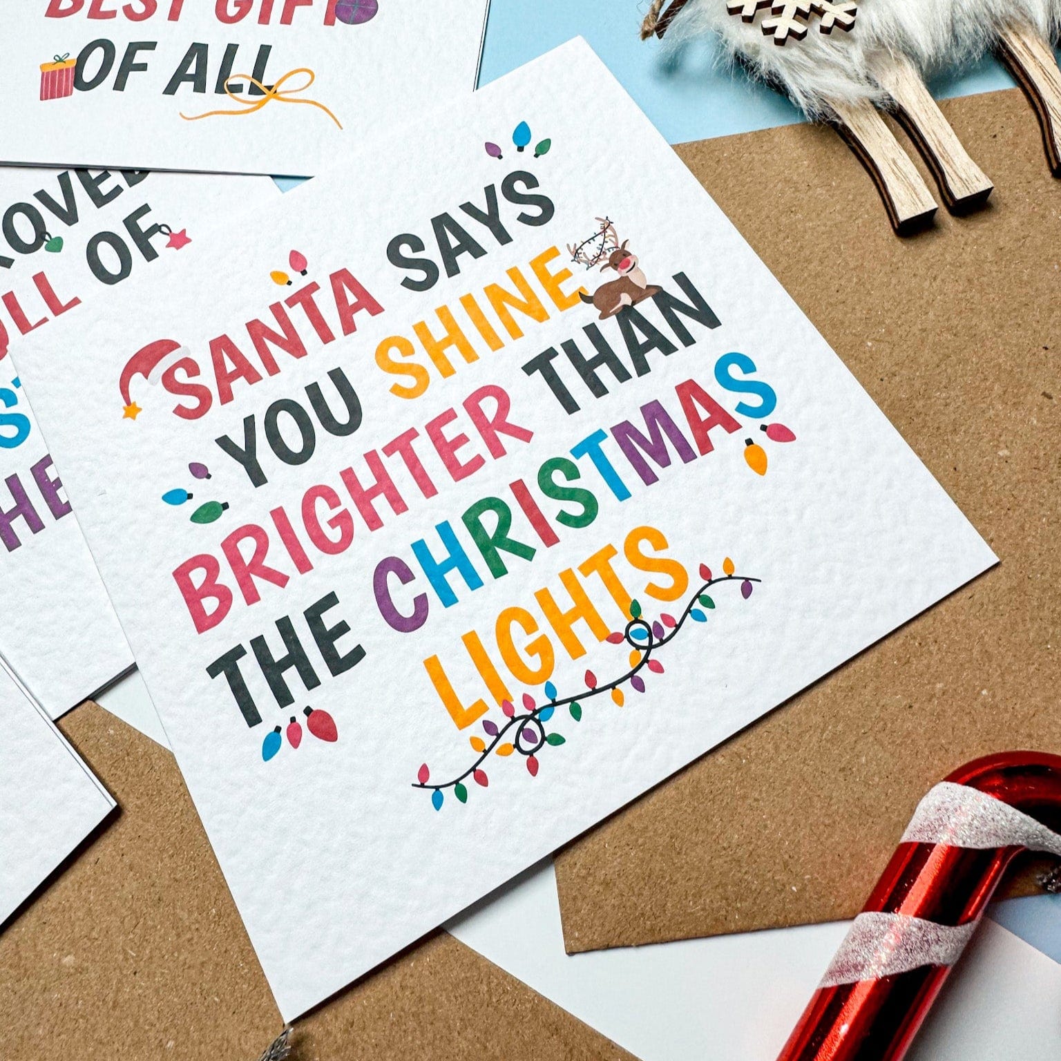Colorful Christmas-themed cards with decorative elements on a wooden surface.