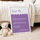 Purple 'Dear Me' print in a relaxed setting, propped against a blanket with a plush bunny alongside.