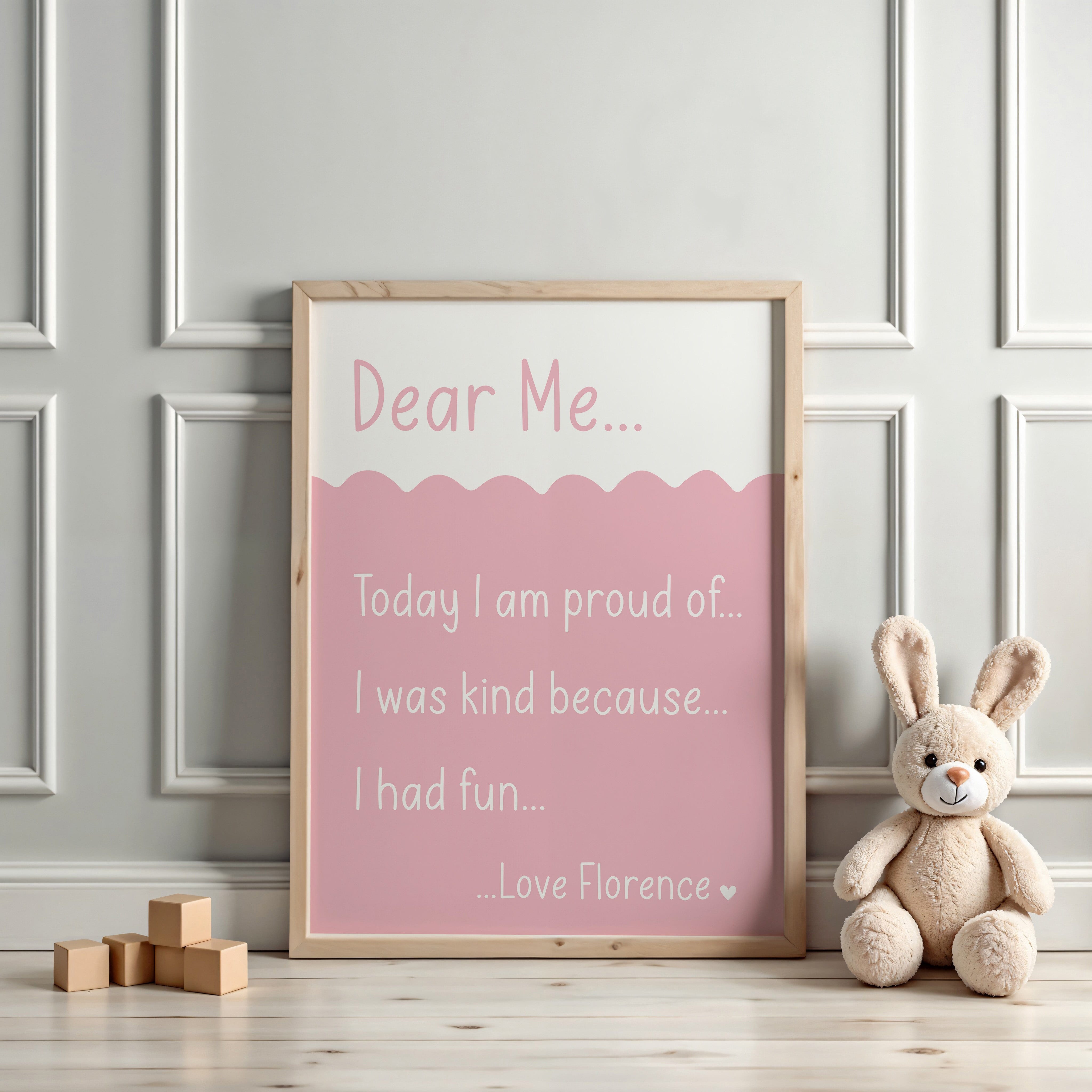 Light pink 'Dear Me' affirmation print displayed in a neutral nursery with a cuddly bunny toy beside it.