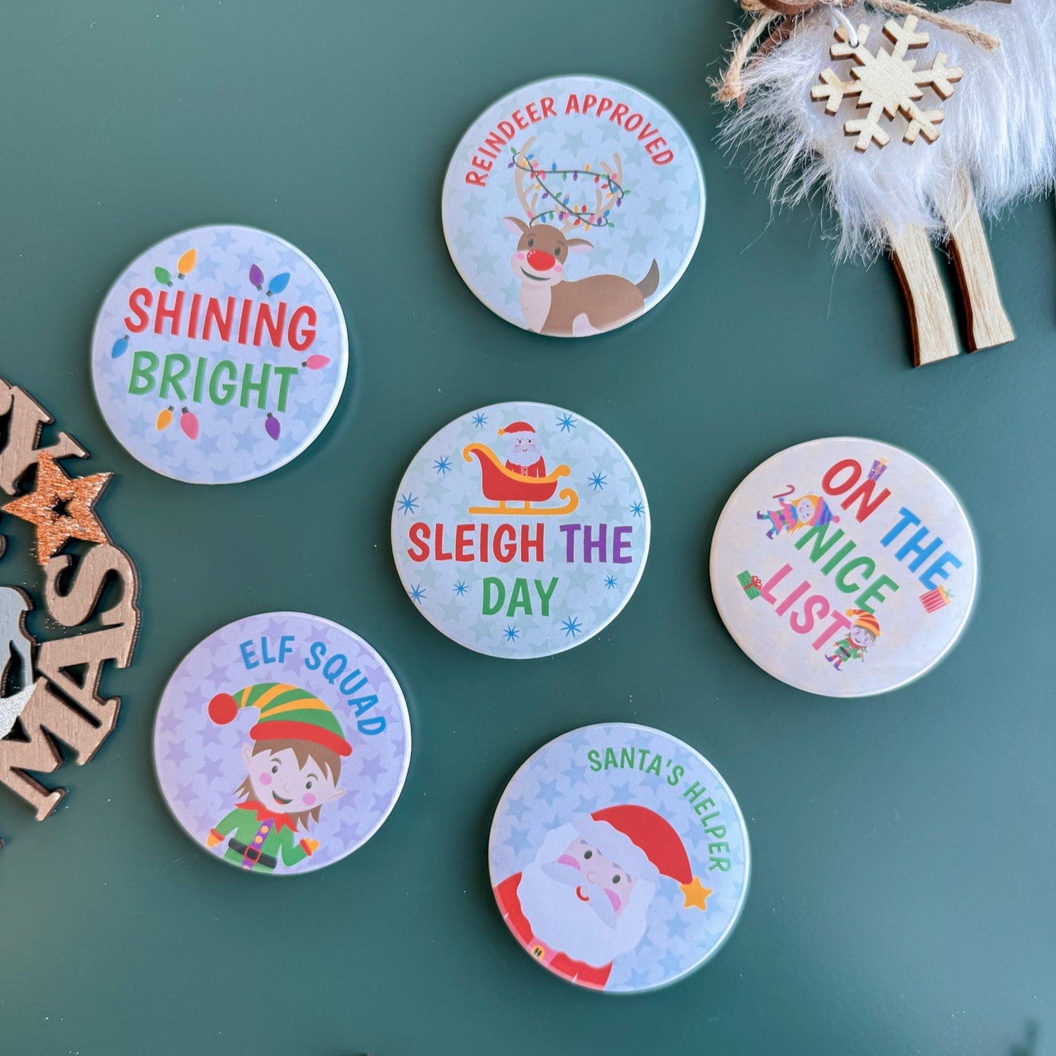 Set of Christmas-themed badges on a green surface with decorative elements.