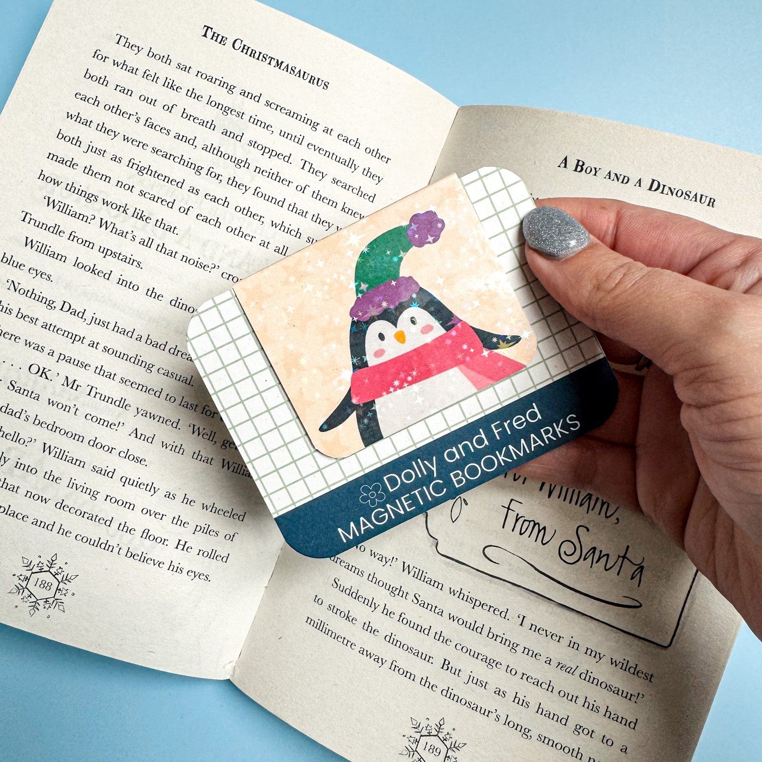 Magnetic bookmarks with penguin design held over an open book