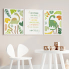 Set of 3 green dinosaur and personalised affirmation prints displayed vertically on a wall in a room with white furniture.