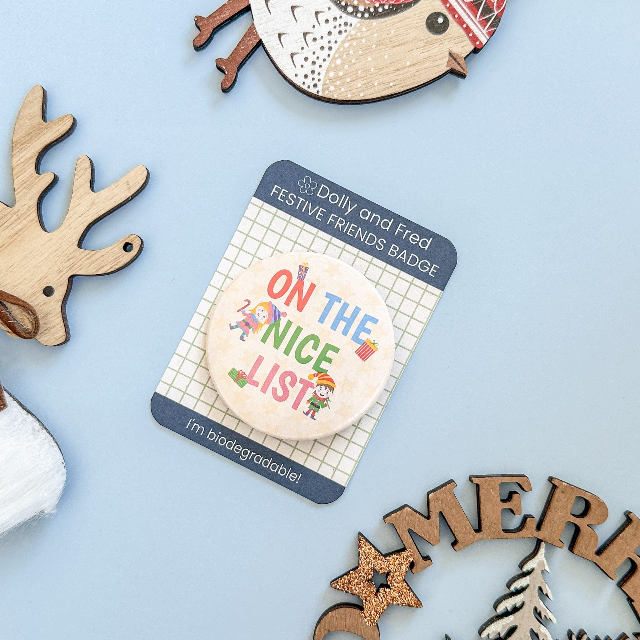 Festive badge with 'On the Nice List' text on a blue background with wooden reindeer and Christmas decorations.