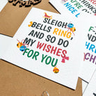 Holiday-themed cards with festive text and graphics on a cardboard surface.