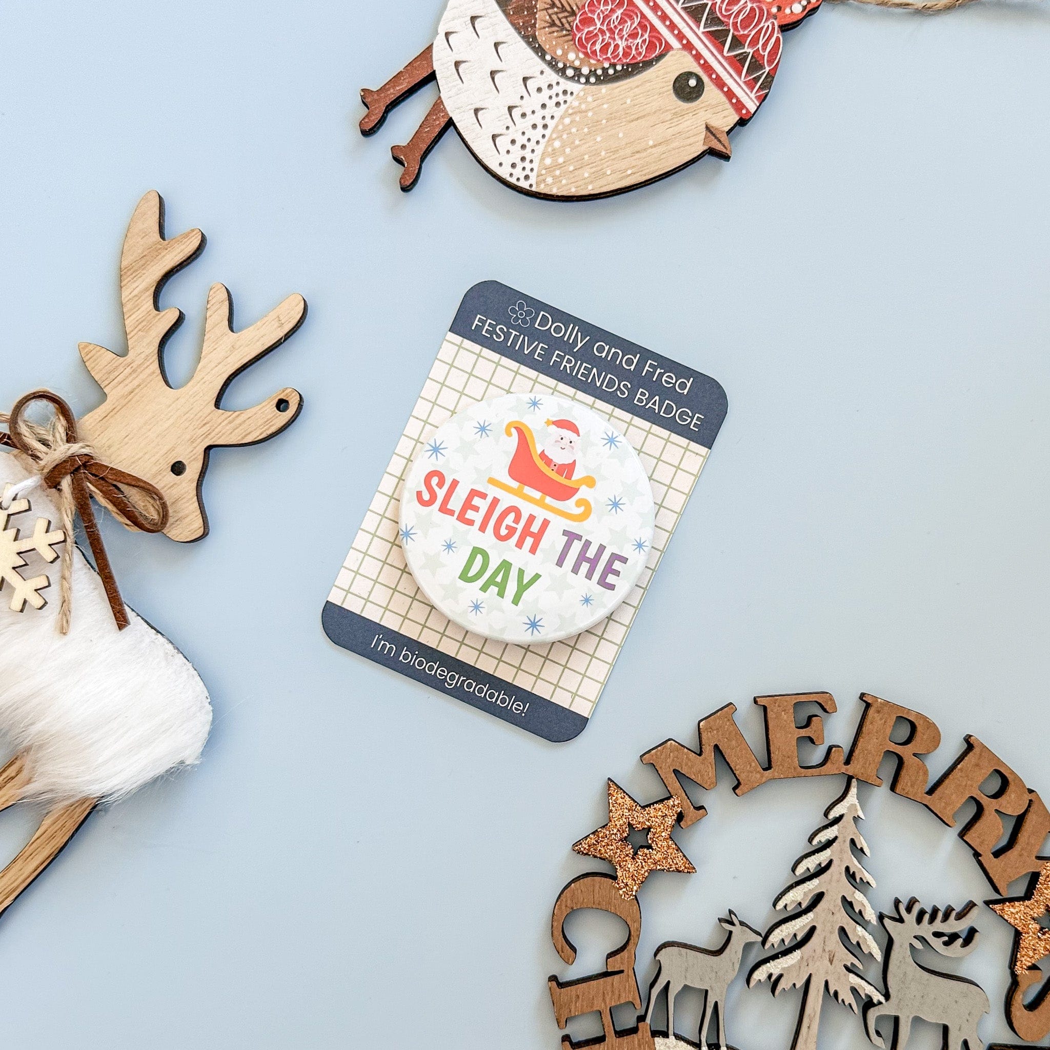 Festive badge with santa design and the text sleigh the day on a blue background