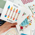 Hand holding multiple personalised thank you cards for teachers.