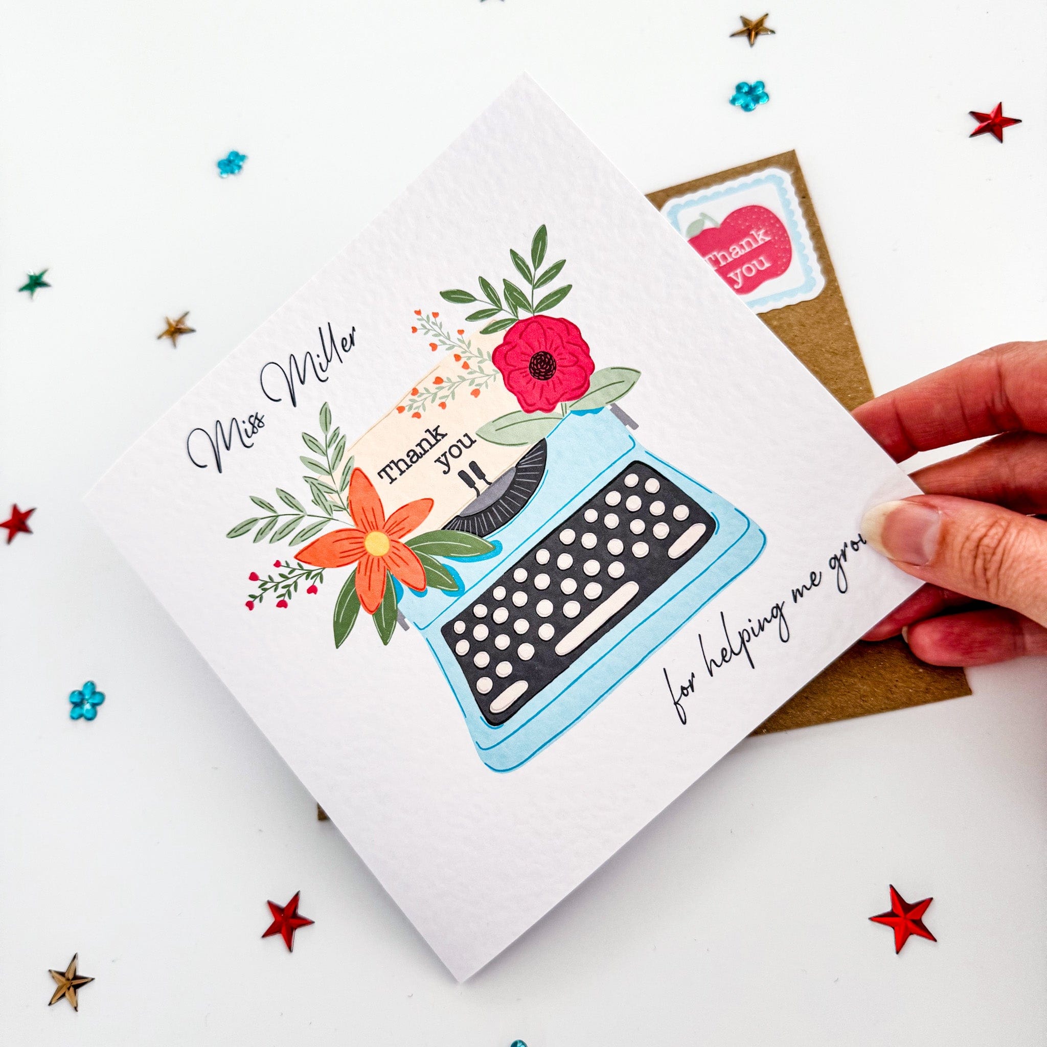 Hand holding a personalised teacher thank you card with a floral typewriter design and "Thank you for helping me grow" message – a sweet end-of-year gift.