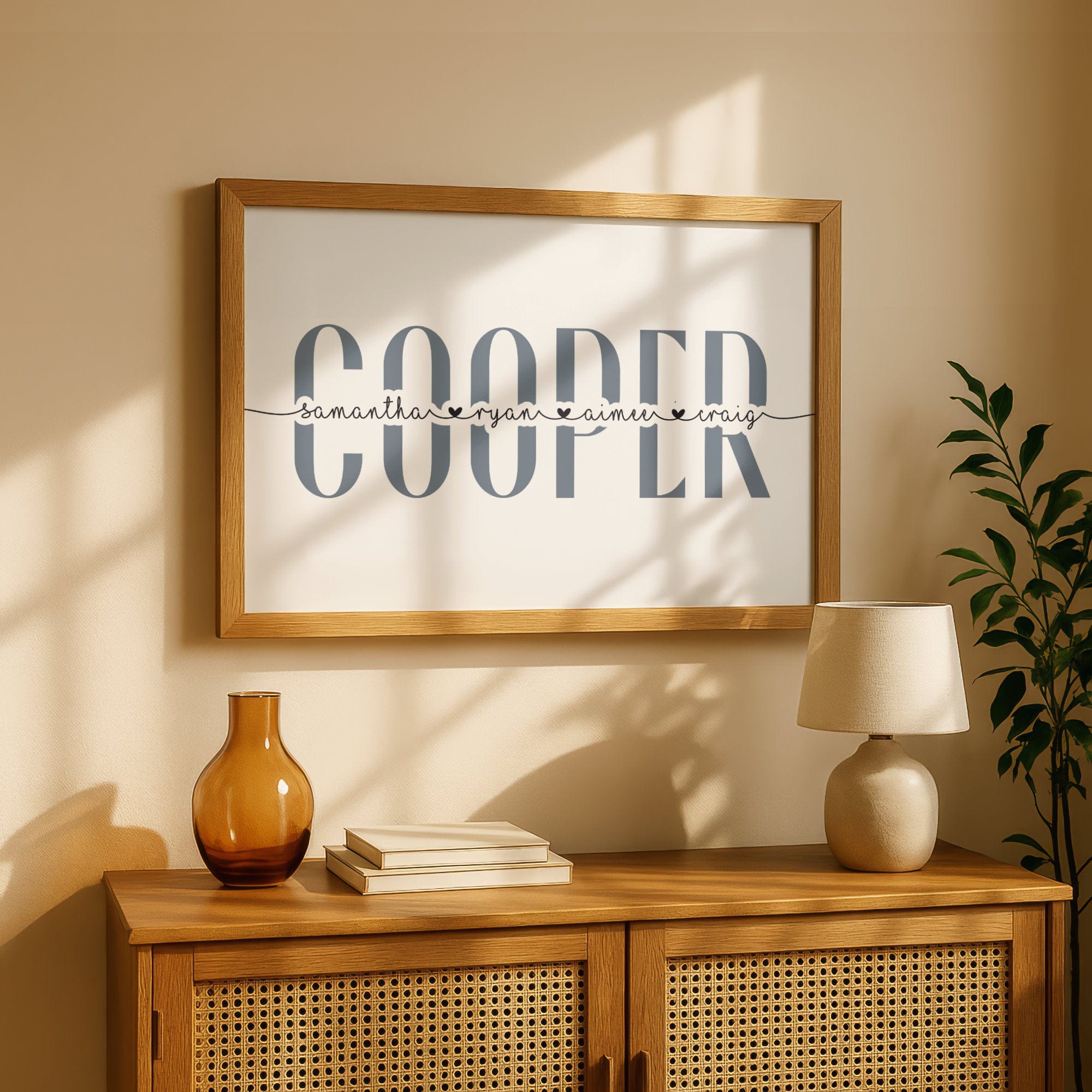 Framed artwork with the surname 'Cooper' on a wall above a wooden cabinet with decor items.