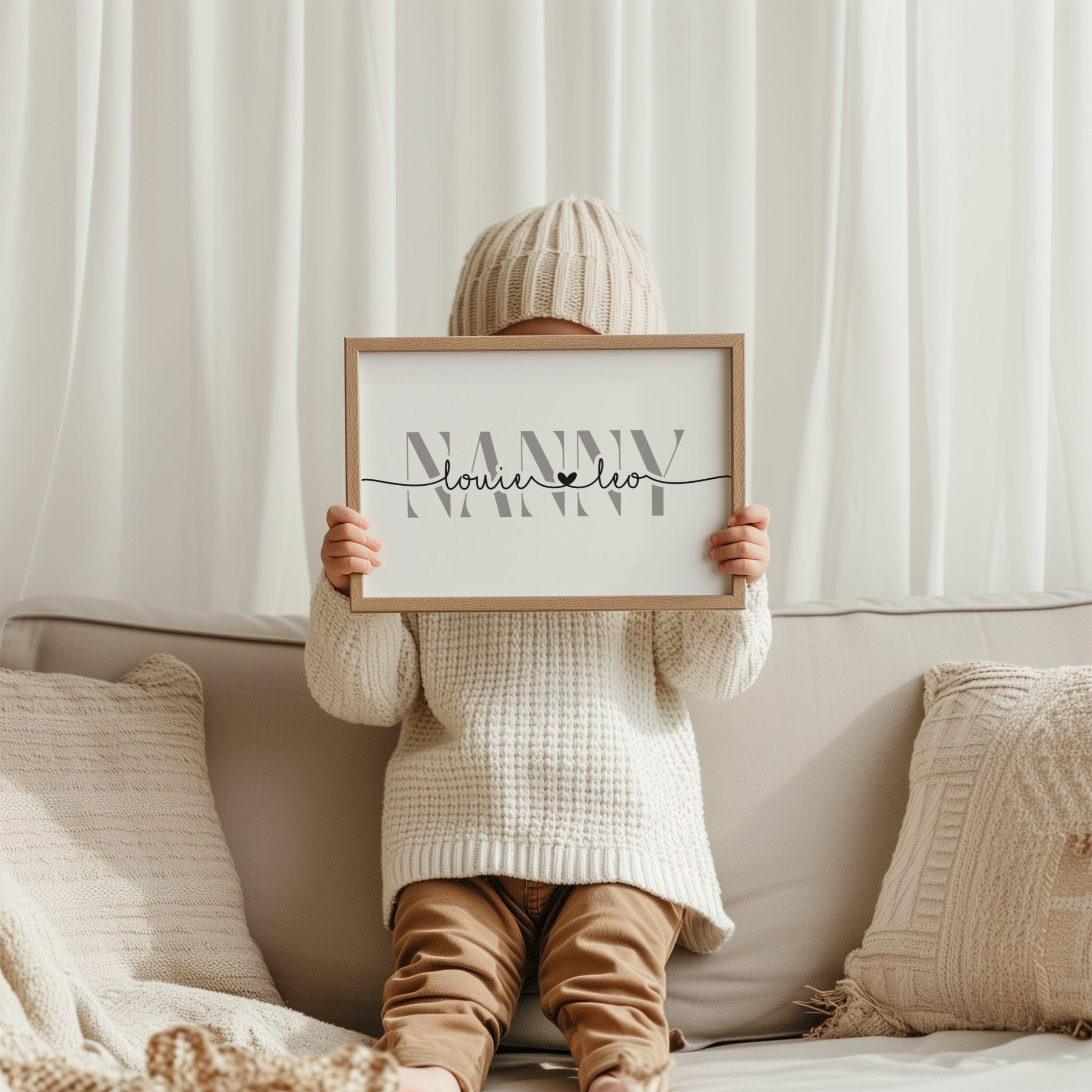 Person sitting on a couch holding a framed picture with 'Nanny' text.
