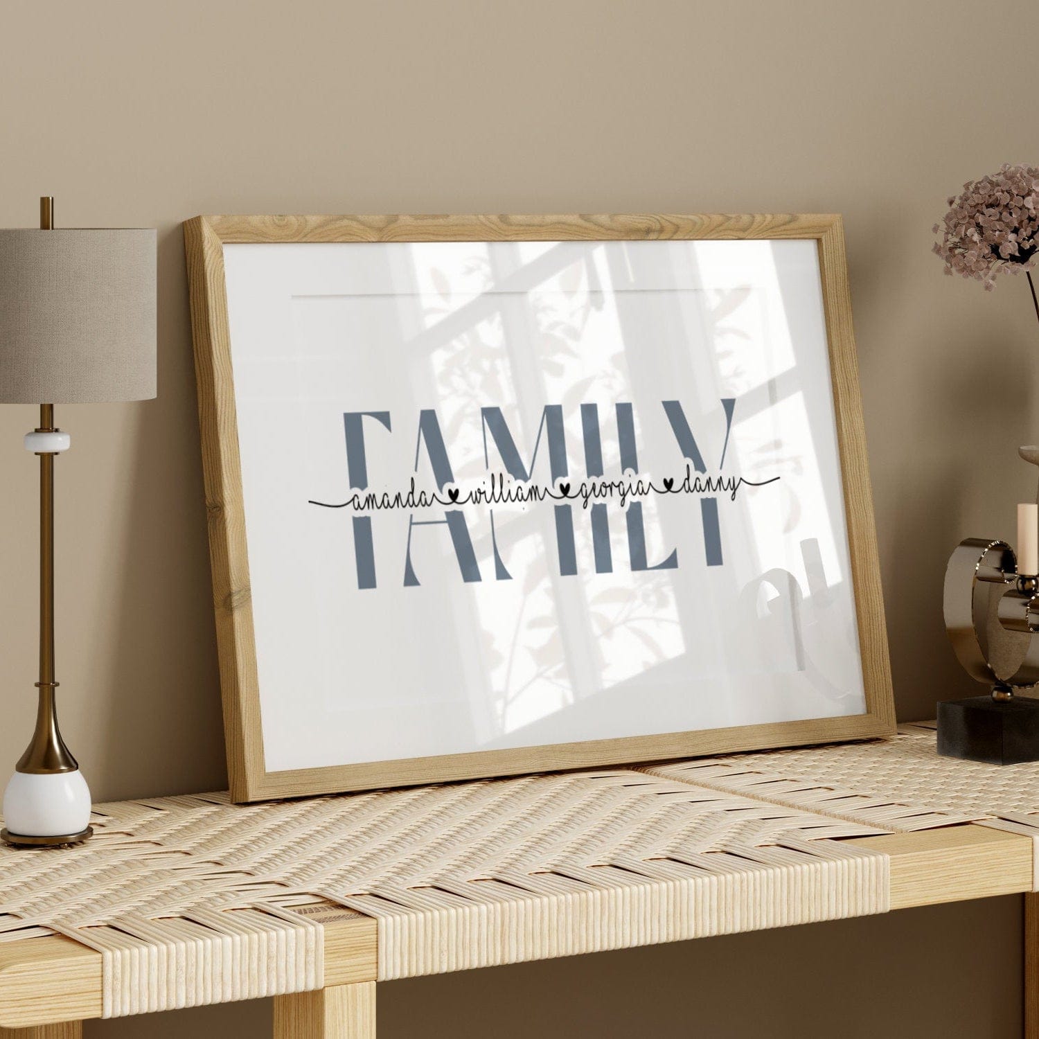 Framed artwork with 'Family' text on a wooden table against a beige wall.