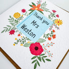 Close-up of red flower thank you card with teacher name and kraft envelope.