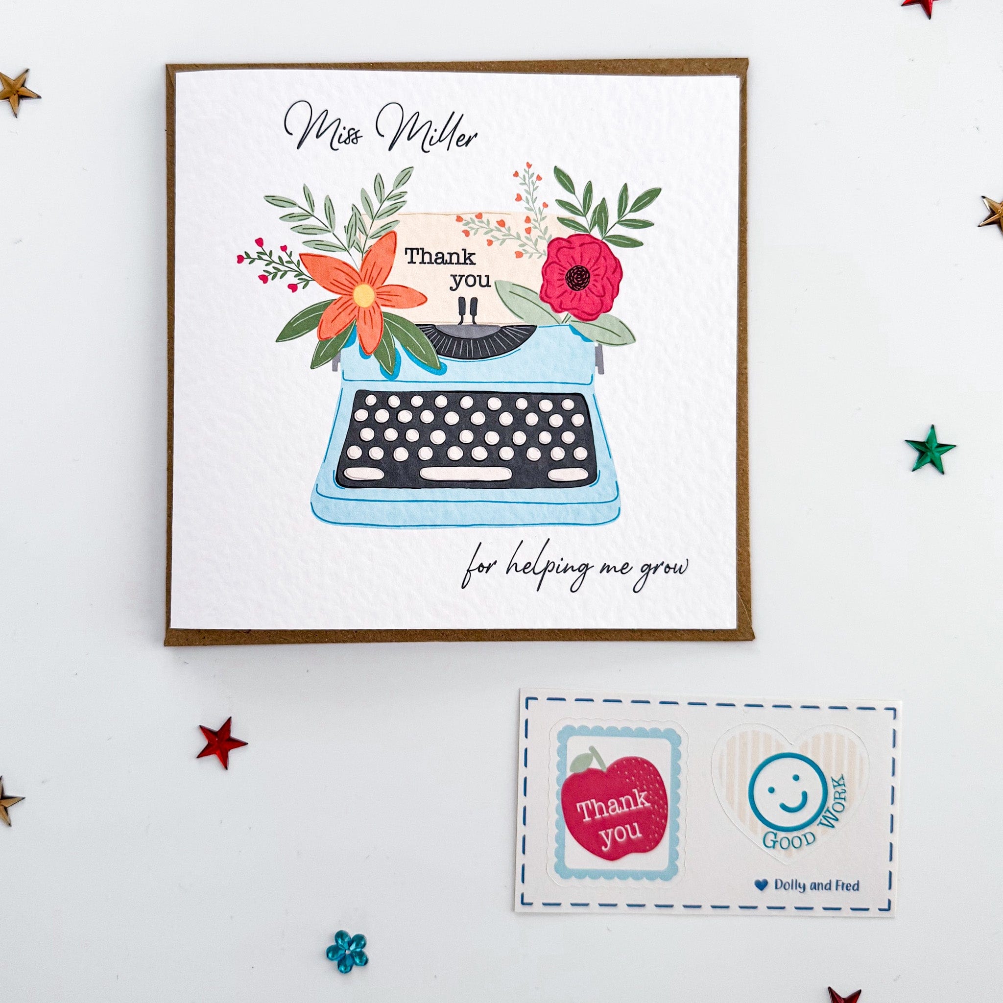 Flatlay of personalised typewriter thank you card for teachers, with bright floral details and thank you message – shown with matching stickers and star confetti.