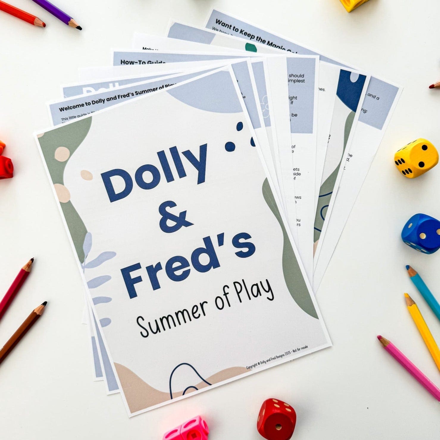 The Dolly and Fred Summer of Play Guide surrounded by pencils and dice