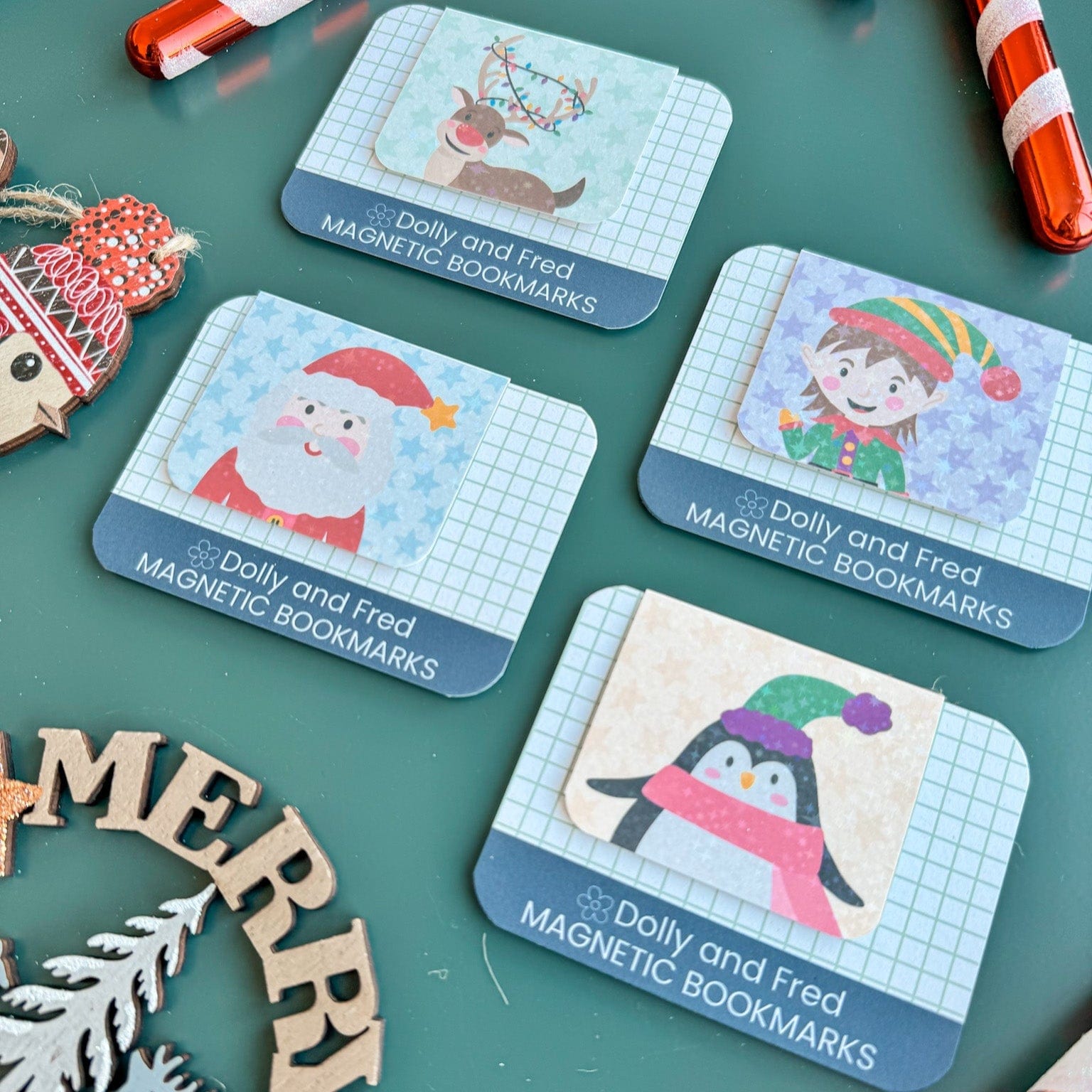 Set of Dolly and Fred magnetic bookmarks with Christmas-themed illustrations on a green surface.