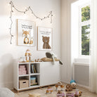 Children's room with white bookshelf, toys, and framed animal prints on a light-colored wall.