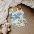 Colorful print with a dinosaur and leaves design on a textured surface with a teddy bear.