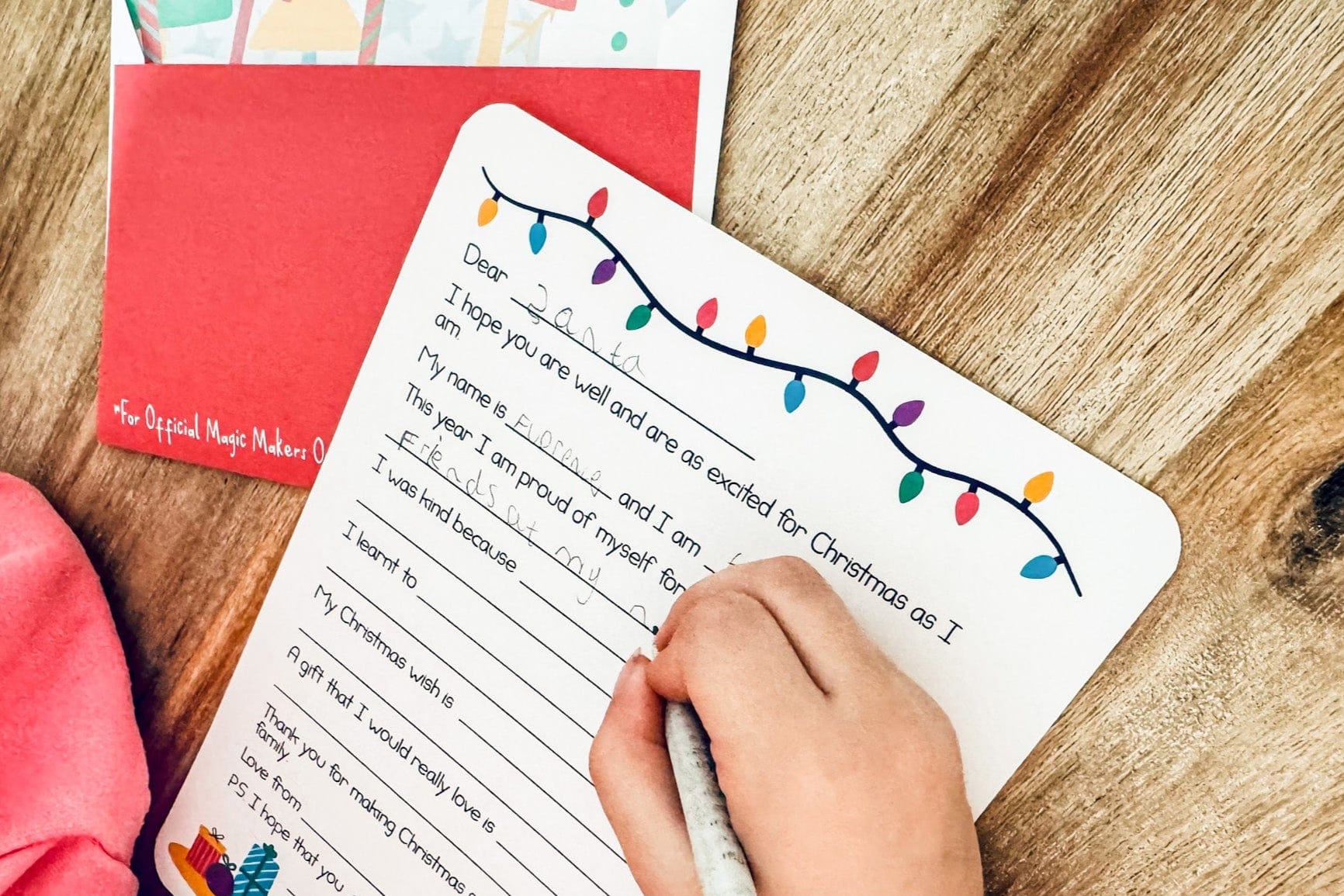 girl writing her letter to santa with a festive themed envelope
