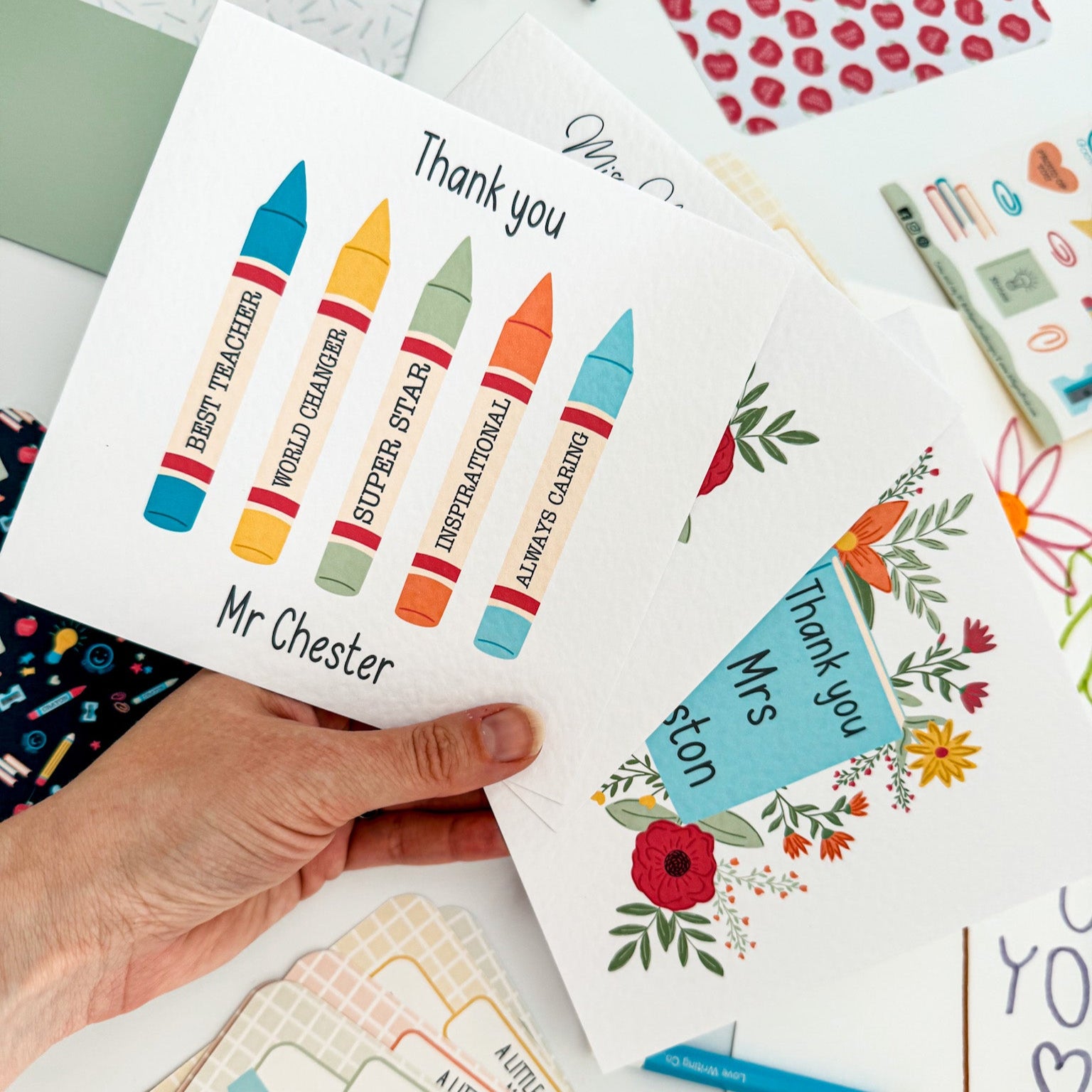 Hand holding multiple personalised thank you cards for teachers.