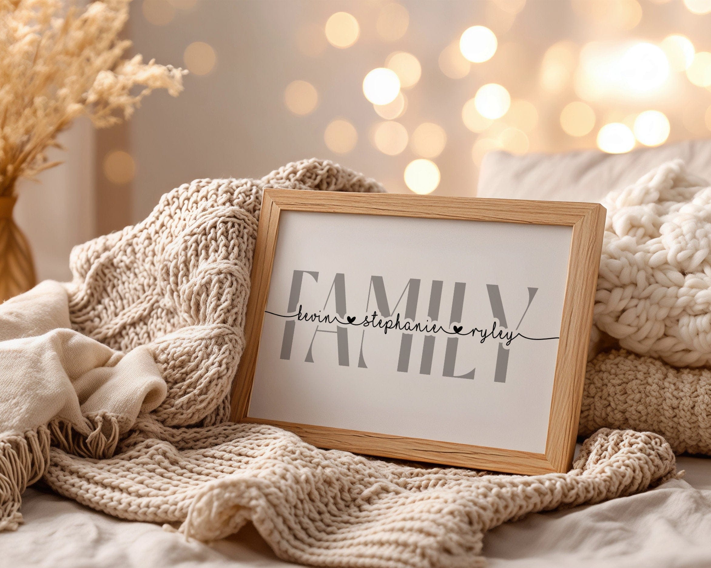 Framed 'Family' sign with personalized names on a cozy blanket with blurred lights in the background