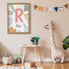 Children's room with a framed picture, stuffed giraffe, and decorative items on a beige wall.