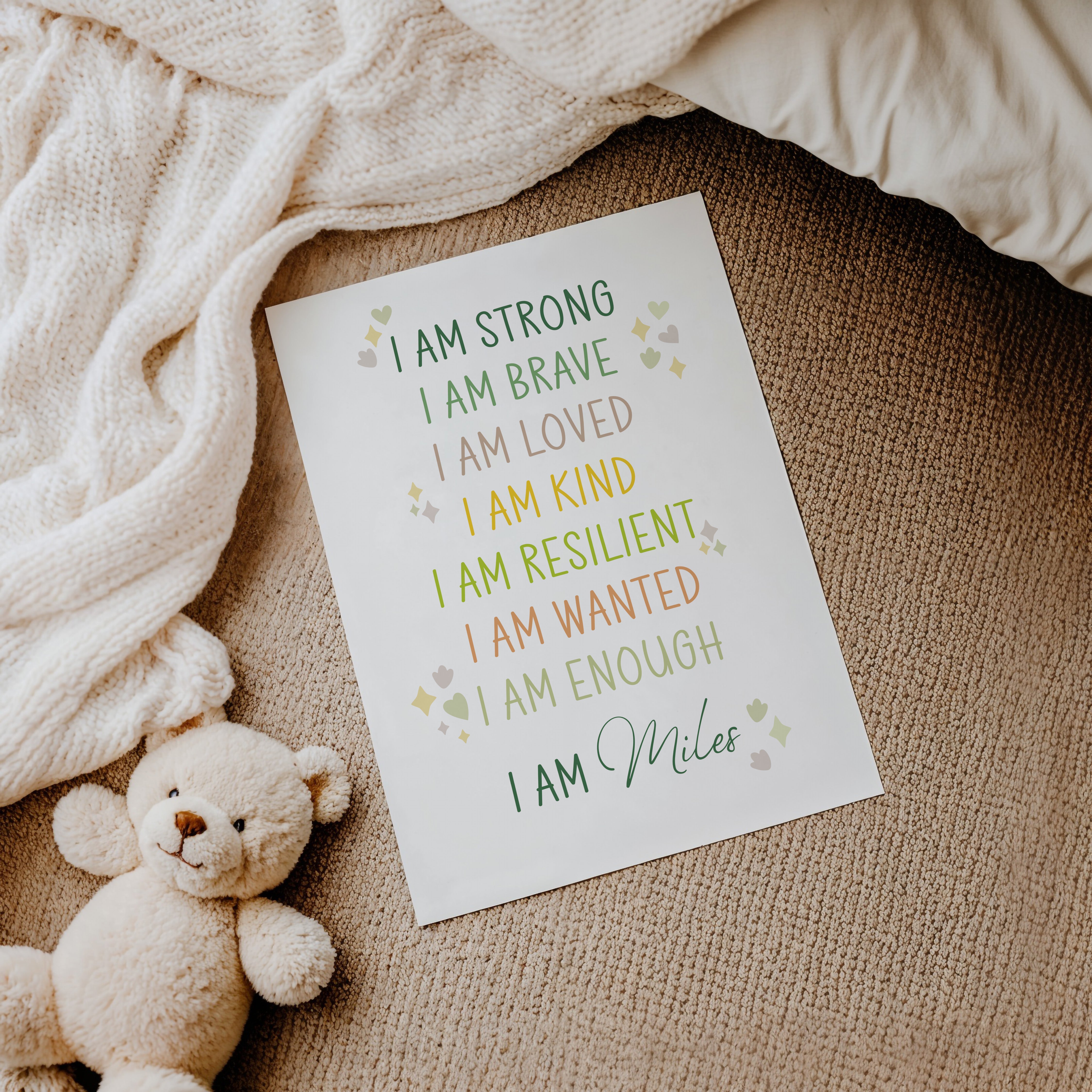 Flat lay of dinosaur affirmation print with child's name, soft cuddly toy, and blanket for cosy detail.