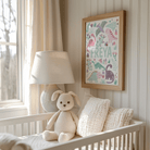 Nursery room with a crib, stuffed animal, lamp, and framed artwork on the wall.