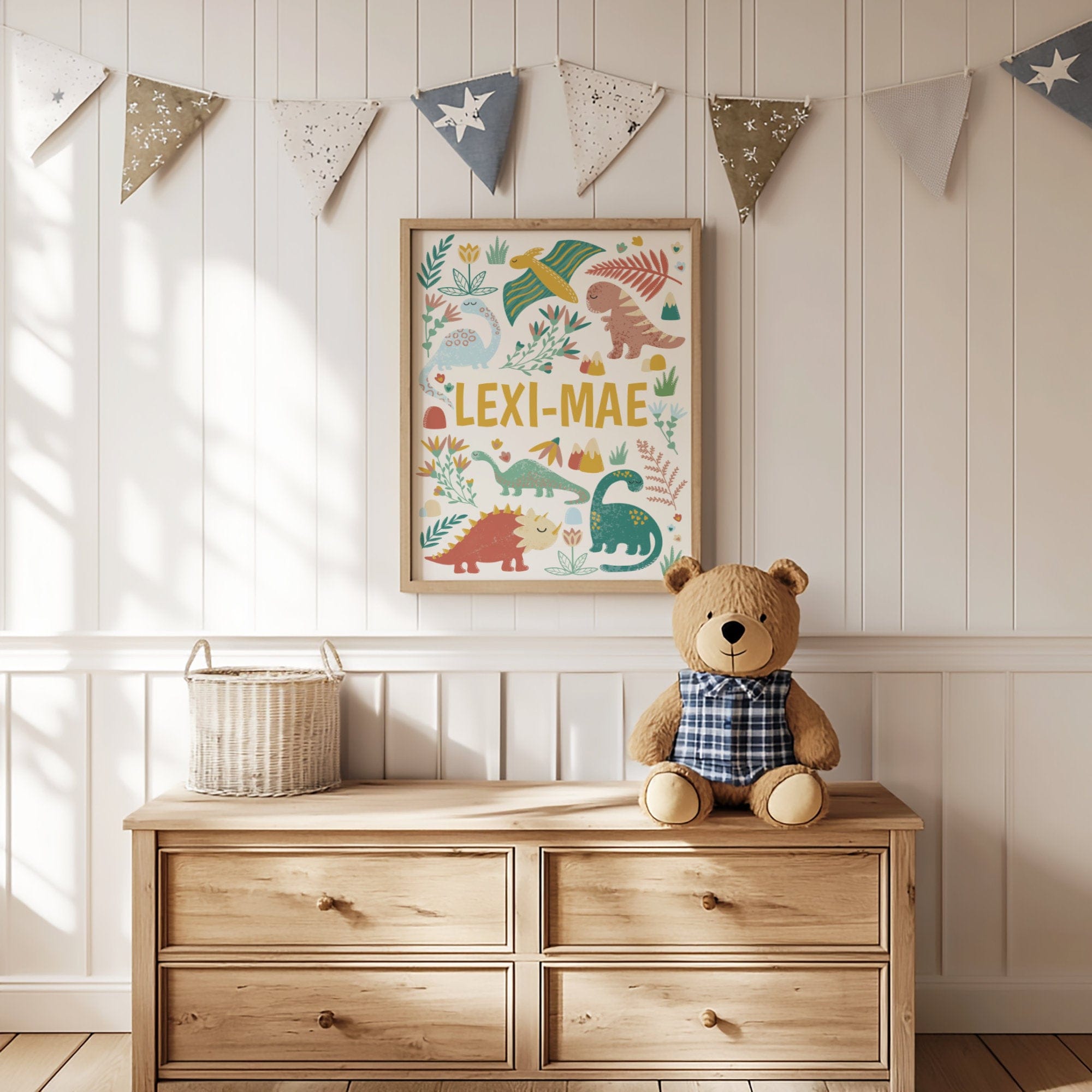 Wooden dresser with teddy bear, basket, and framed dinosaur artwork in a nursery setting.