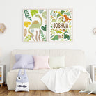 Two dinosaur-themed wall art prints above a couch with colorful pillows and a blanket.