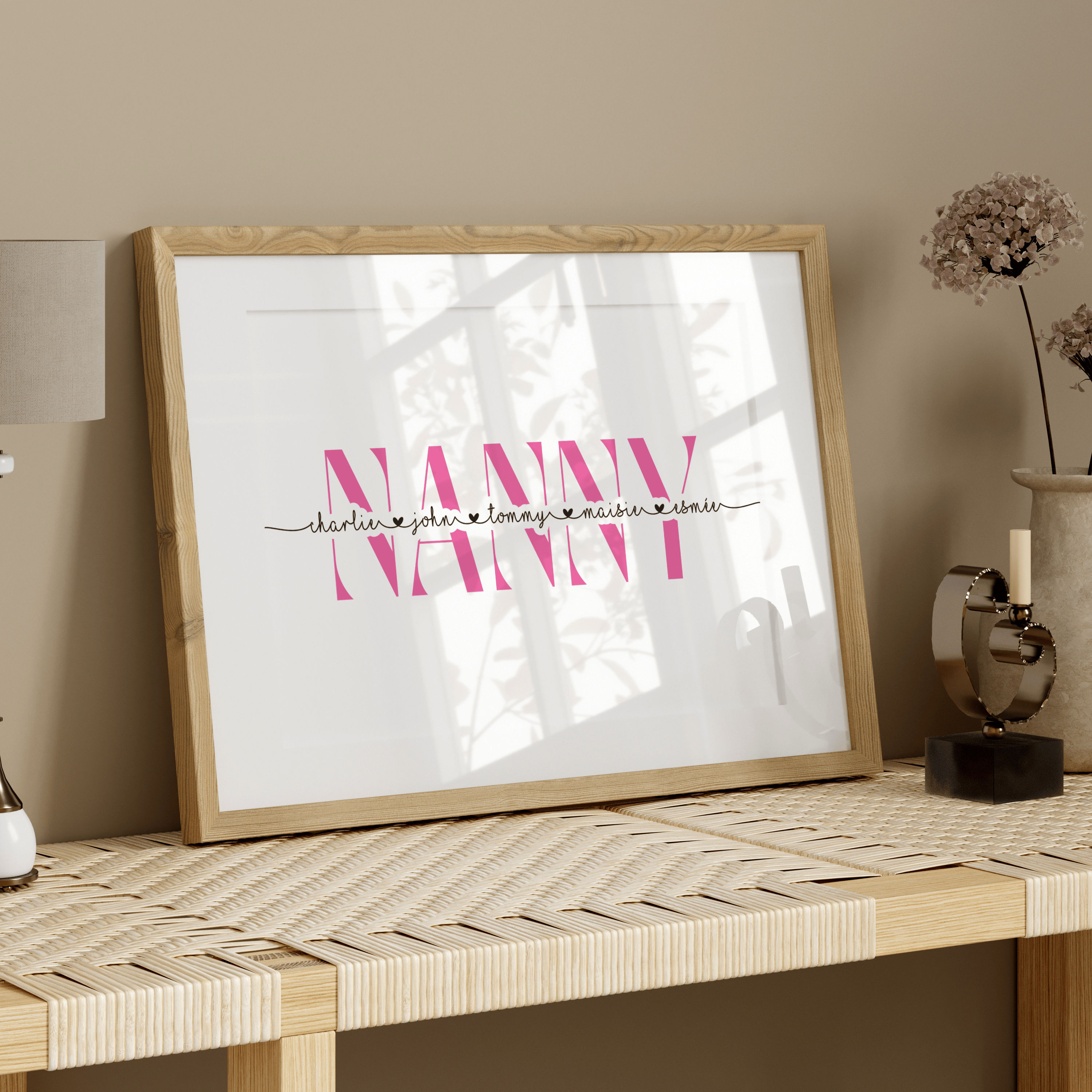 Framed artwork with 'NANNY' on a table against a beige wall