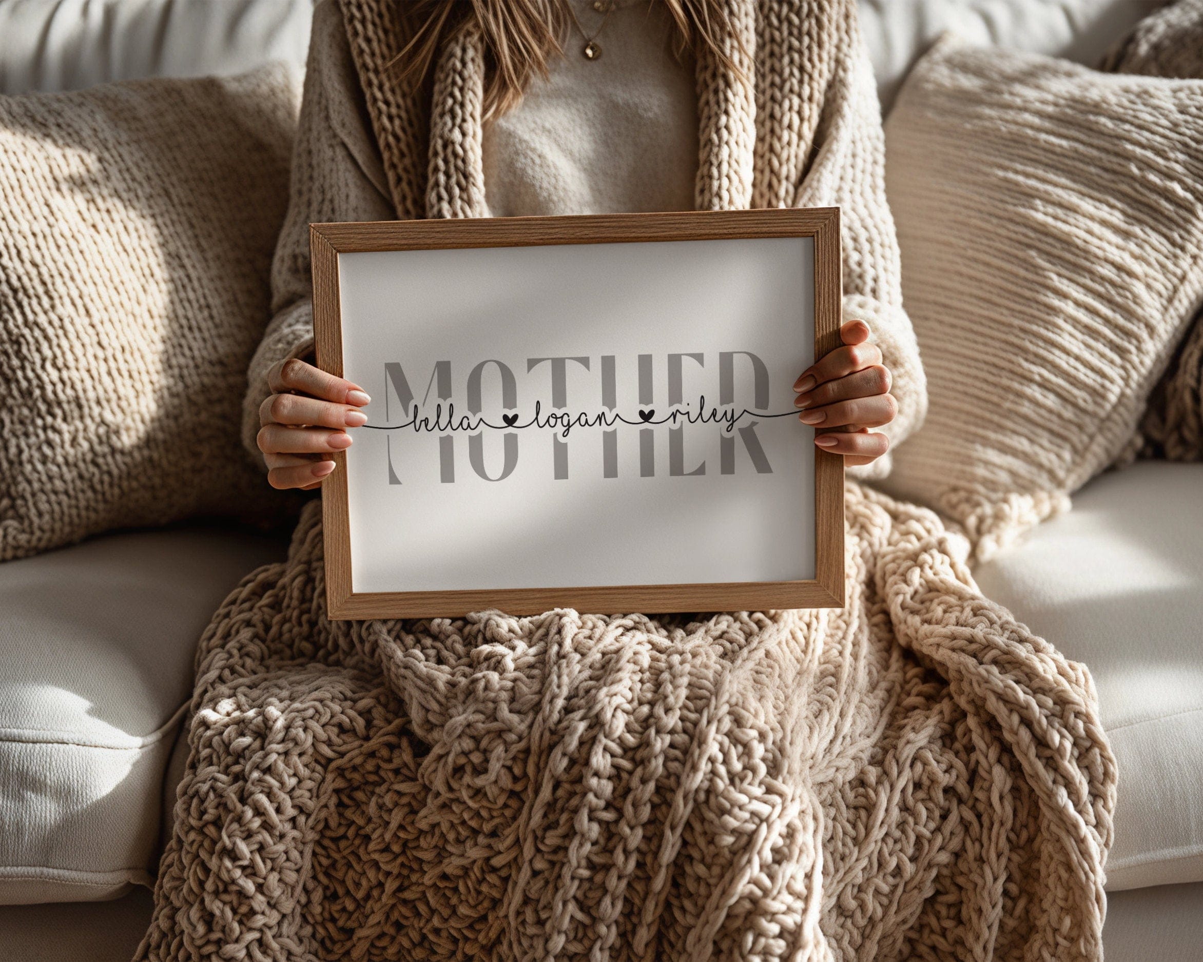 Person holding a framed sign with 'MOTHER' and 'hello, my name is' text on a cozy sofa.