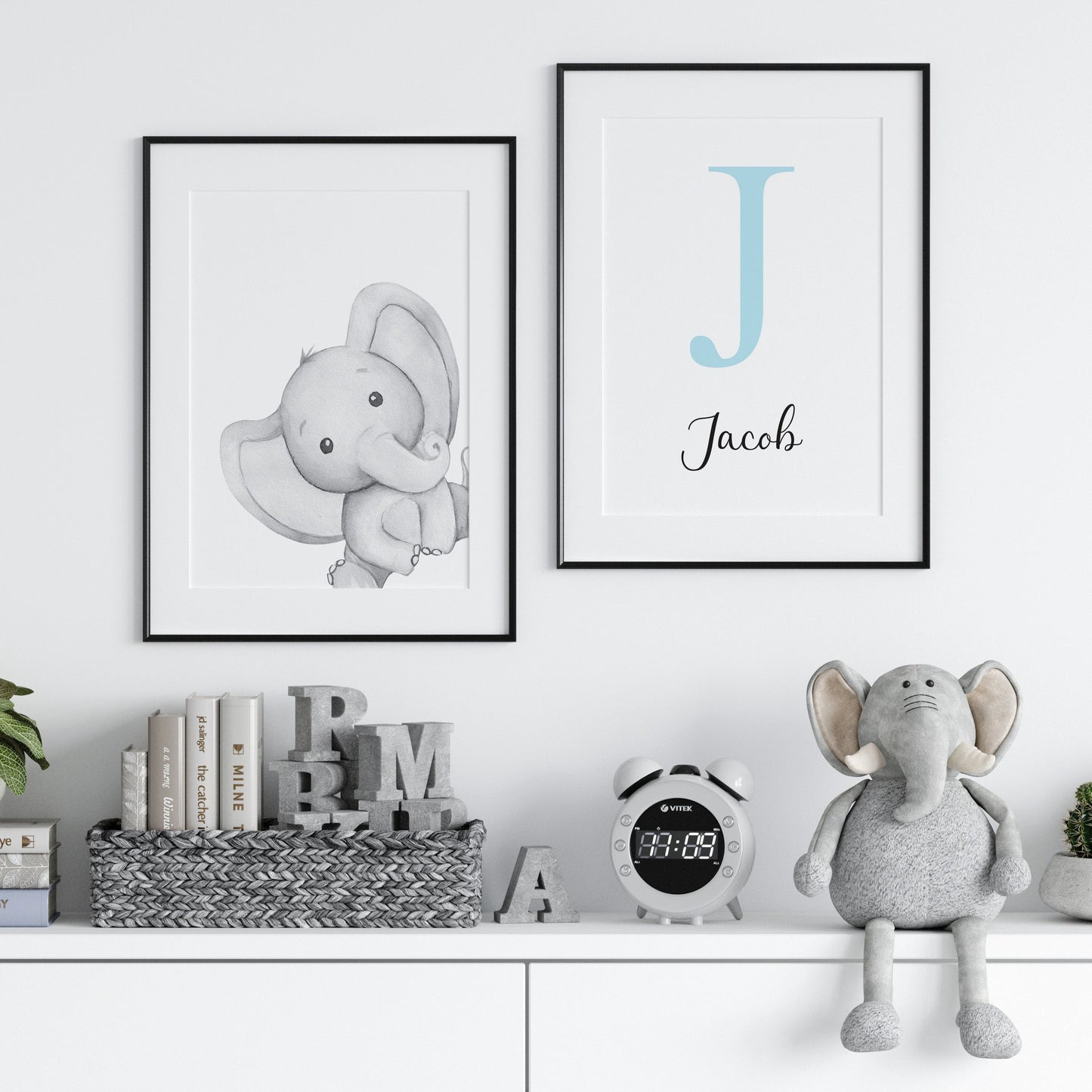 Grey elephant printed onto white paper hung in a black froame with a light blue initial print next to it and cute elephant plush sitting on a shelf - Dolly and Fred
